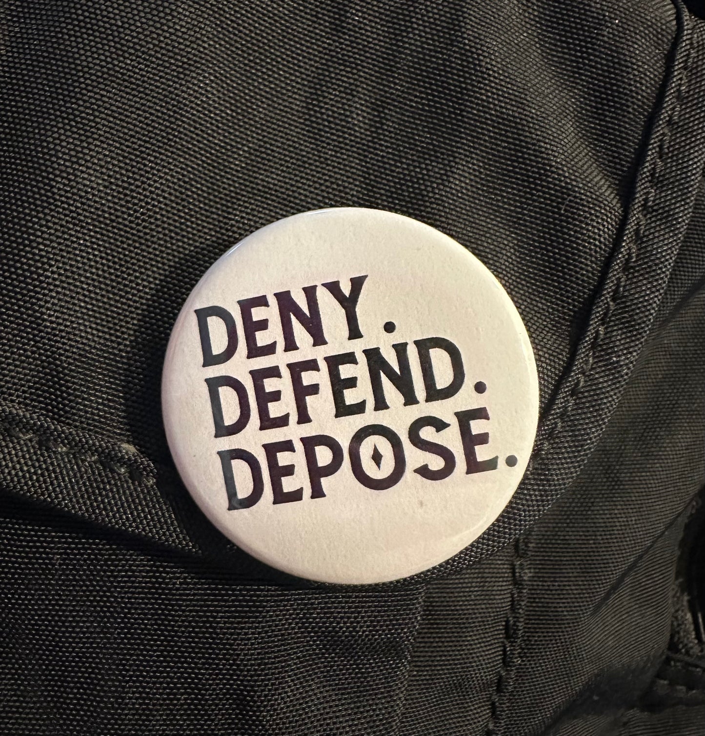 Deny. Defend. Depose. Button